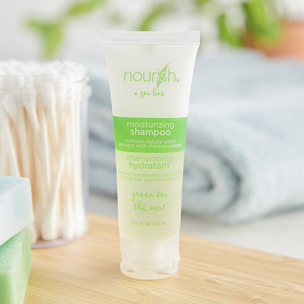 A white plastic bottle of Nourish Green Tea Shampoo with green text.