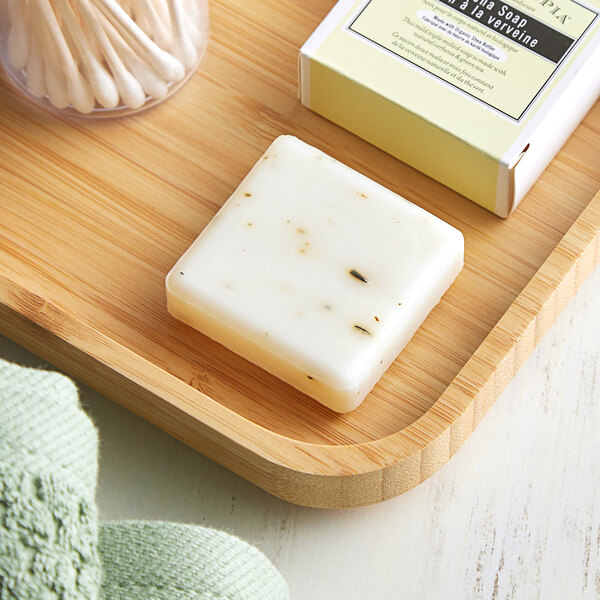 A wooden tray with a Pharmacopia Verbena body soap bar and cotton buds on it.