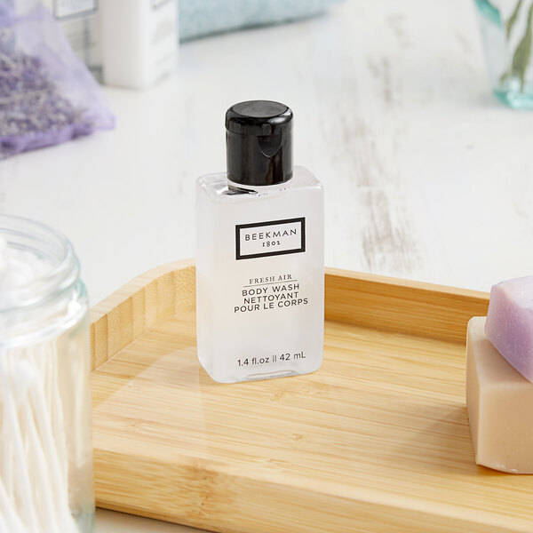 A small white bottle of Beekman 1802 Fresh Air body wash on a wooden tray.
