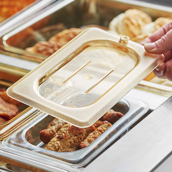 A hand using a Cambro amber flat lid to cover food in a pan.