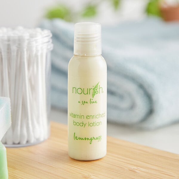 A case of Nourish Lemongrass Body Lotion bottles on a table next to a towel.