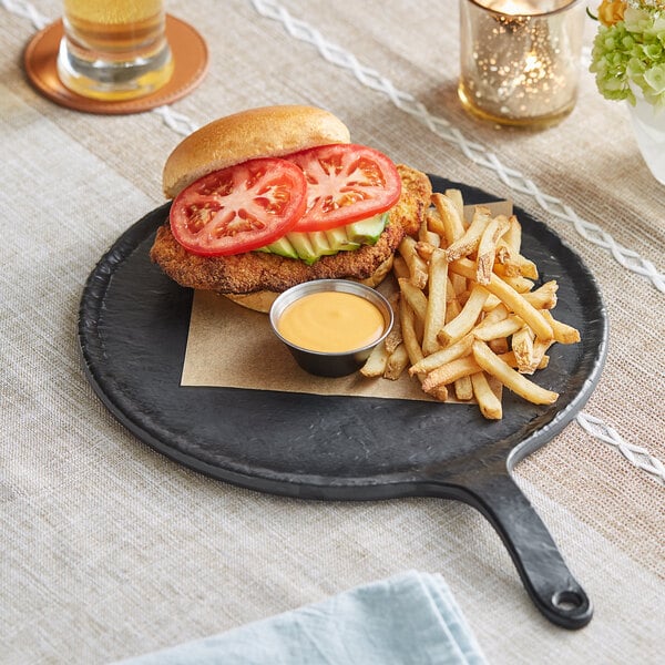 An Acopa faux slate melamine serving board with a sandwich and fries on it.