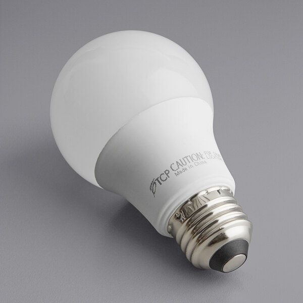 A TCP 9W dimmable LED light bulb with a black and white label on a gray surface.