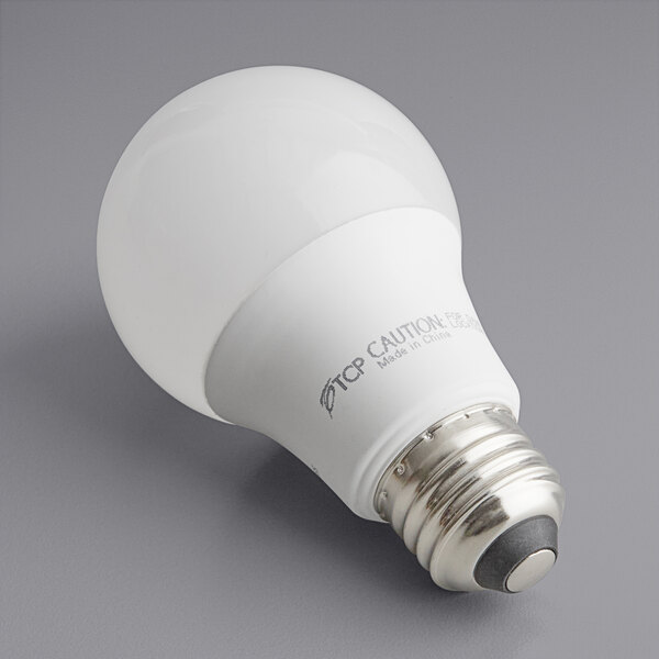 A TCP 9W dimmable LED light bulb on a gray surface.