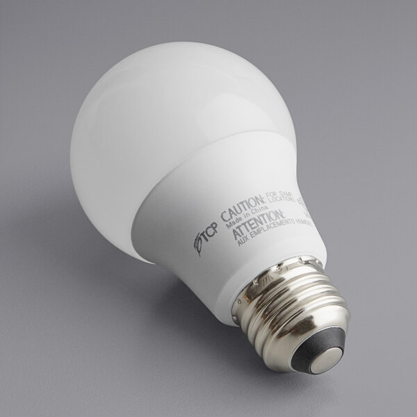 A TCP dimmable LED light bulb with a black base on a gray surface.