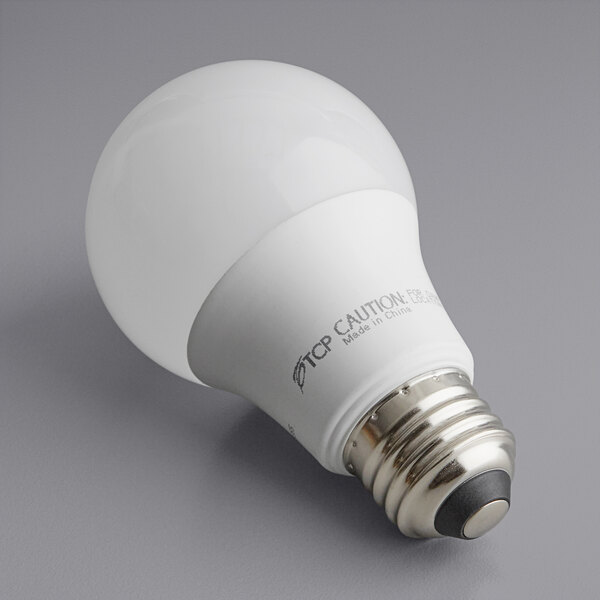 A TCP 9W dimmable LED light bulb with a white label on a gray surface.