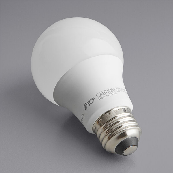 A TCP 9W LED light bulb with a white base and label on a gray surface.