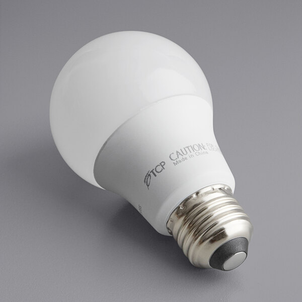 A TCP dimmable LED light bulb with white packaging on a gray surface.