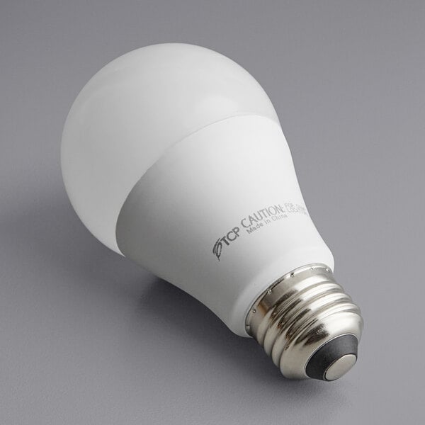 A TCP dimmable LED light bulb in its packaging on a gray surface.