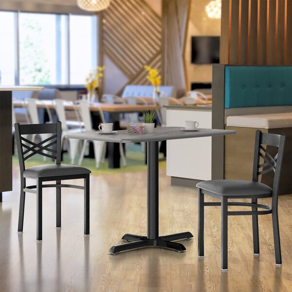 A Lancaster Table & Seating table and base in a restaurant dining area with white and black stripes.