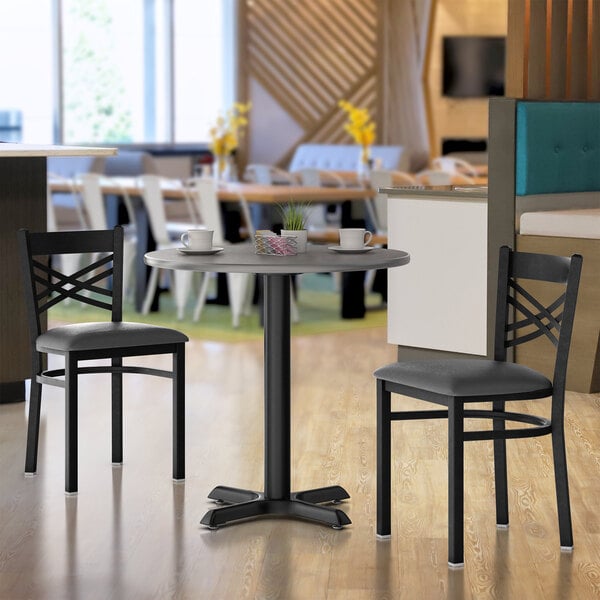 A Lancaster Table & Seating table and base with a white and gray top on a table in a restaurant.