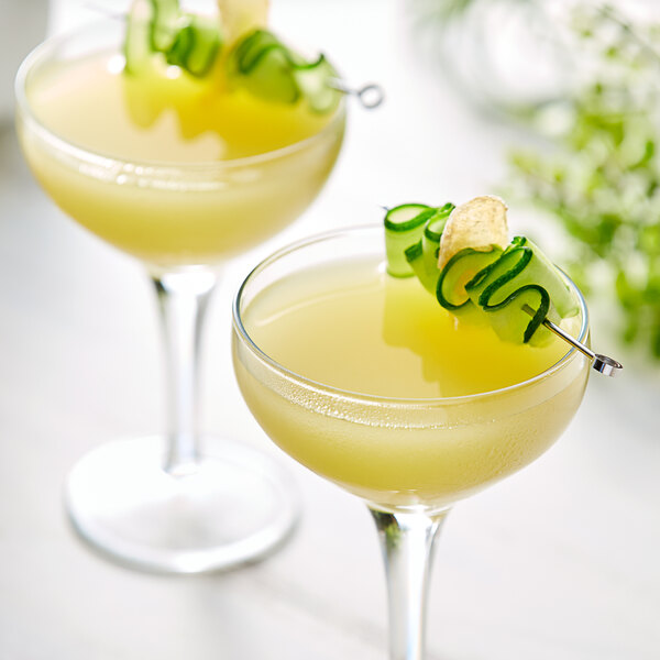 Two glasses of Les Vergers Boiron Ginger Puree cocktails with cucumber garnish.