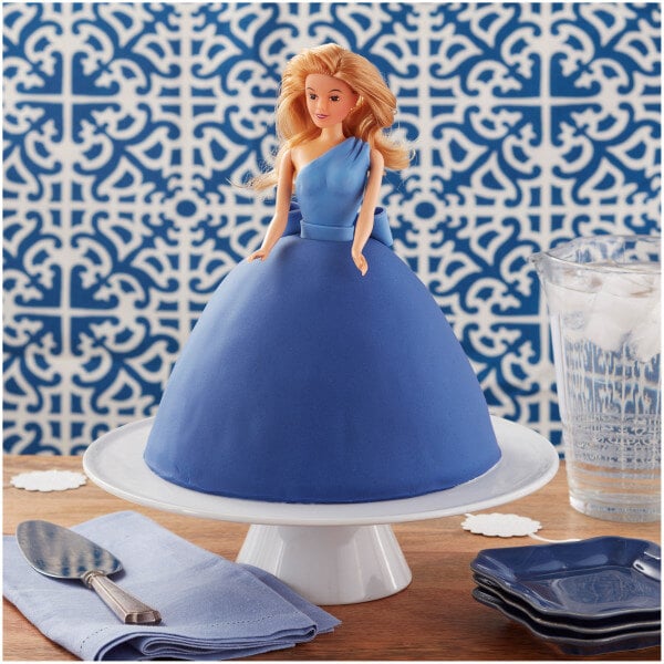 A blue cake with a Wilton doll cake topper with a blonde doll in a blue dress.