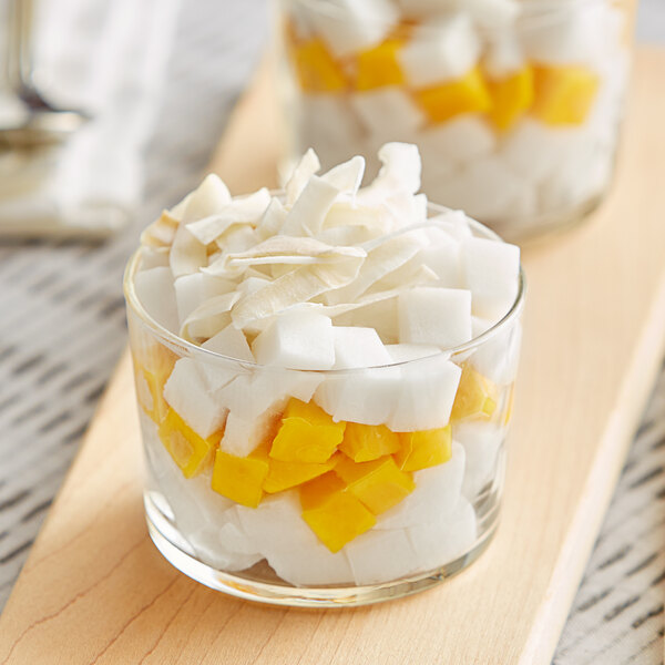 Two small cups of coconut cream and mango puree on a wood surface.
