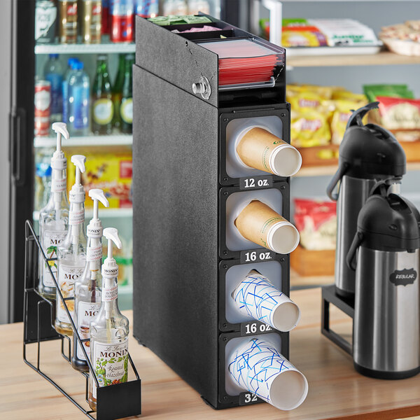 A KleanTake black countertop cup dispenser with straw slots and fast-changing gaskets on a counter.