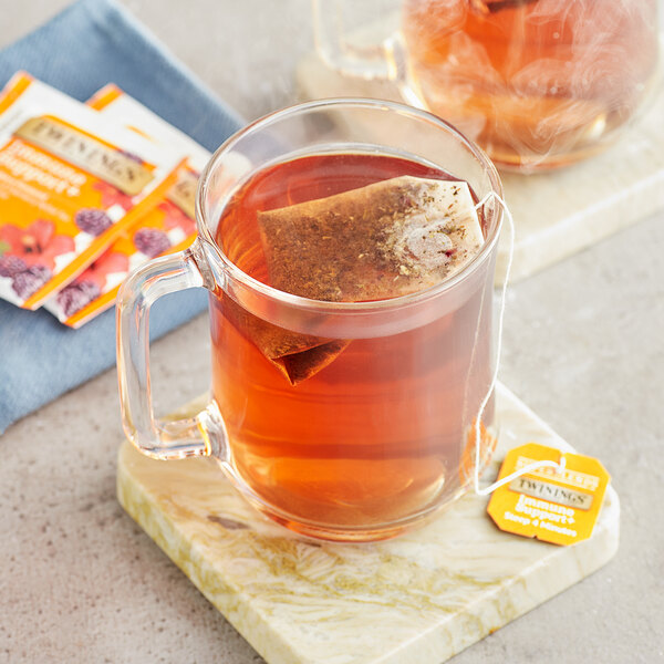 A glass mug of Twinings Superblends Immune Support+ tea with a tea bag in it.