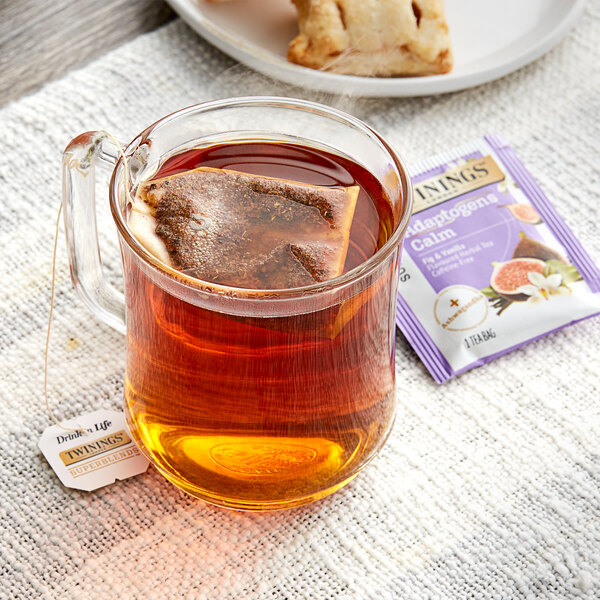 A glass mug of Twinings Fig & Vanilla tea with a tea bag in it.
