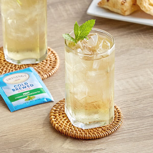A glass of Twinings iced tea with mint leaves on a table.