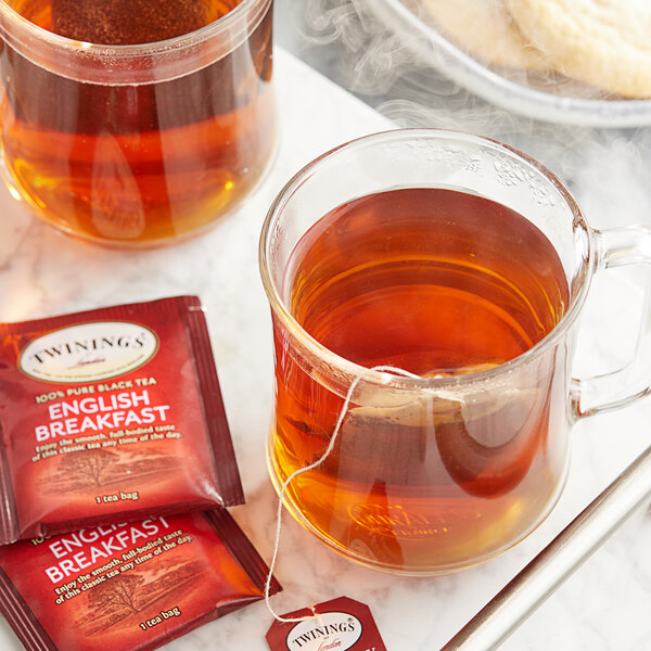 A glass mug of Twinings English Breakfast Tea with a tea bag in it.