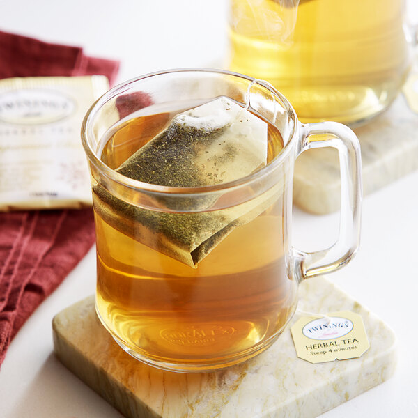 A glass mug of Twinings Peppermint Cheer tea with a tea bag in it.