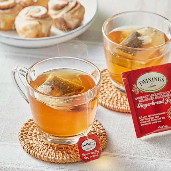 A glass cup of Twinings Gingerbread Joy tea with a tea bag in it.