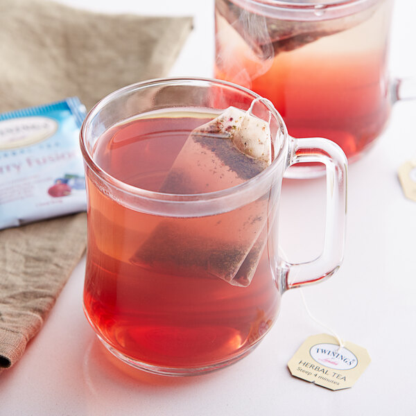 A glass mug with a Twinings Berry Fusion tea bag steeping in it.