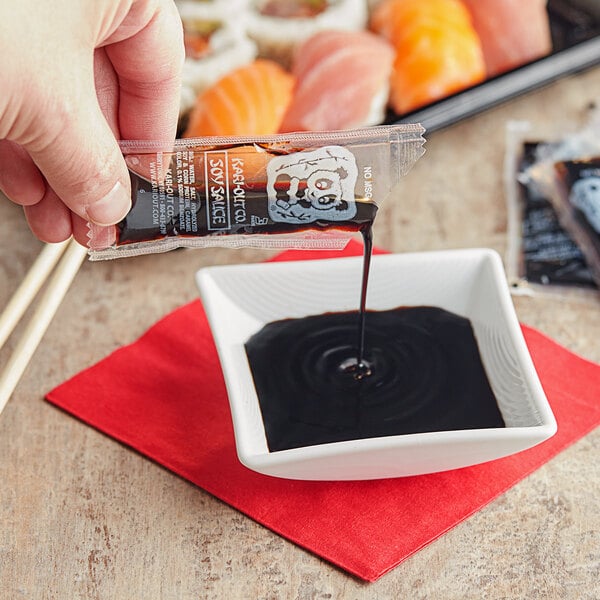 A hand pouring a Soy Sauce portion into a bowl of sushi.