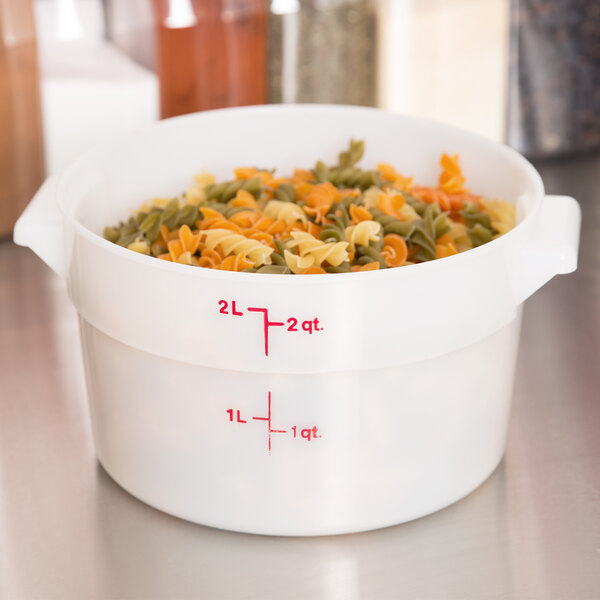 A white Cambro round food storage container filled with multicolored pasta.