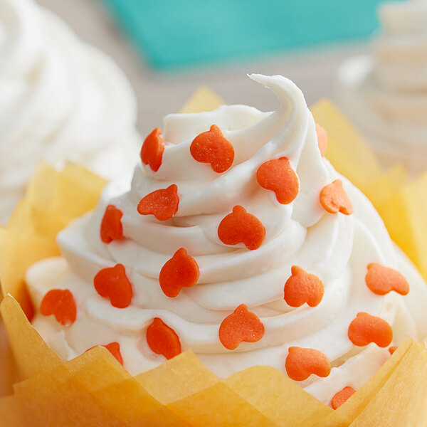 A cupcake with white frosting and orange pumpkin sprinkles.