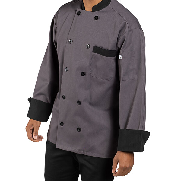 A person wearing a slate gray Uncommon Chef long sleeve chef coat with black trim.