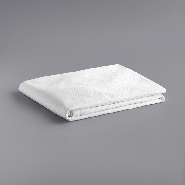 A stack of folded white Oxford Super Blend full size hotel bed toppers.