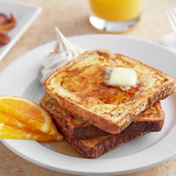 A plate of Papetti's Cinnamon Swirl French Toast with butter and syrup and orange slices.