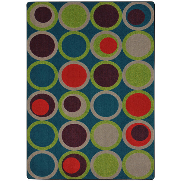 A Joy Carpets area rug with blue, green, and red circles and a green border.