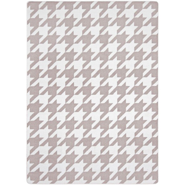 A taupe rectangular area rug with a grey and white houndstooth pattern.