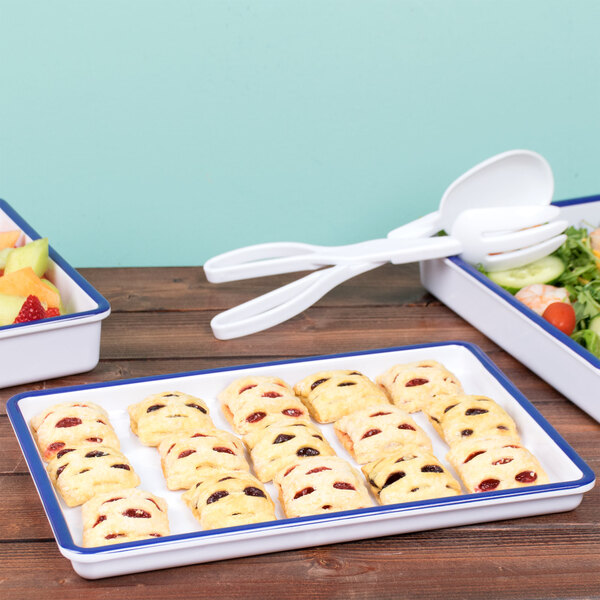 A white rectangular melamine serving tray with a blue rim holding a variety of food and utensils.