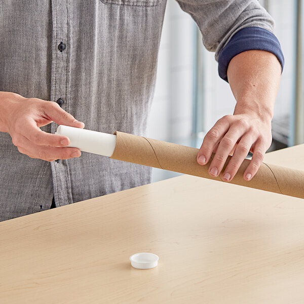 A person holding a Lavex Kraft mailing tube of paper.