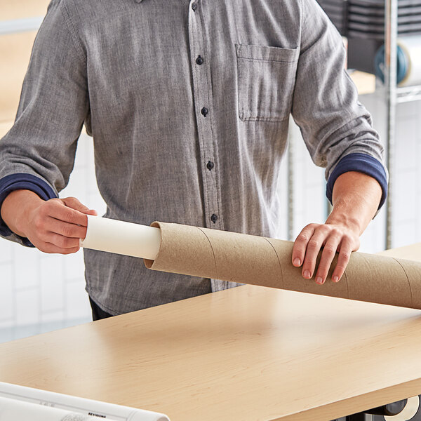 A person holding a Lavex Kraft cardboard mailing tube.
