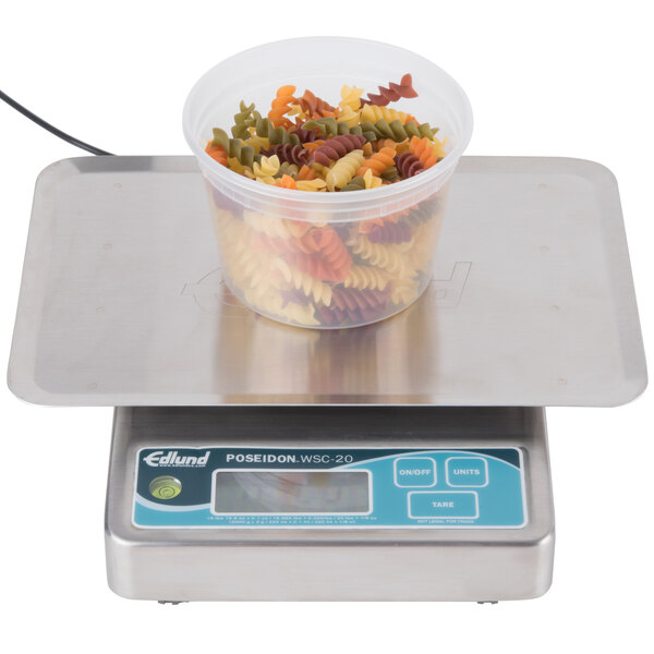 An Edlund Poseidon portion scale with a plastic container of pasta on it.