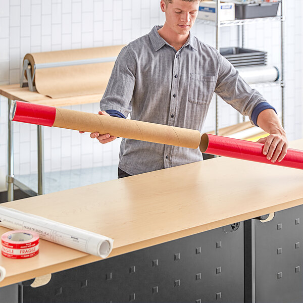 A person holding a long red cardboard tube.