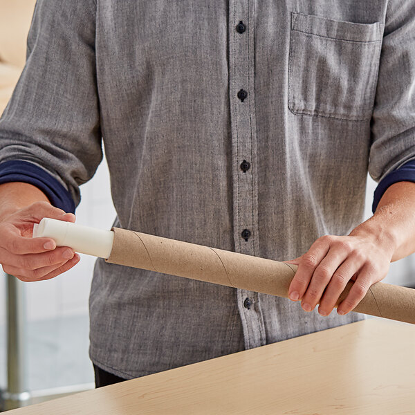 A man holding a Lavex Kraft mailing tube on a counter.
