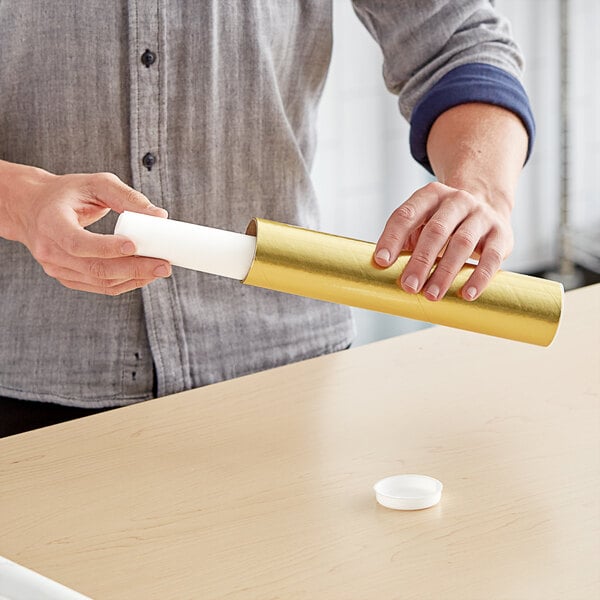 A person holding a gold Lavex Mailing Tube over a white cap.