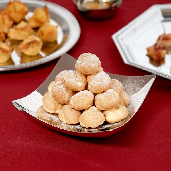 A Vollrath stainless steel platter with a pile of pastries.