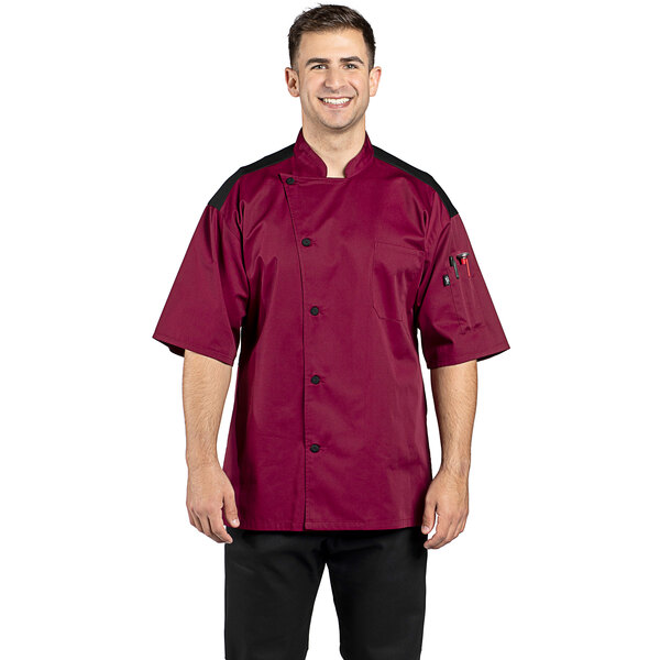 A man wearing a burgundy Uncommon Chef Rogue Pro Vent chef coat with mesh back and short sleeves.