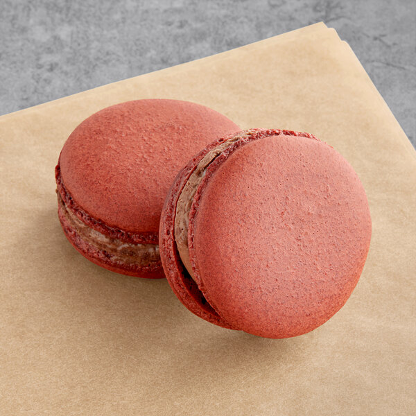 Two red Macaron Centrale vegan macarons on a brown napkin.