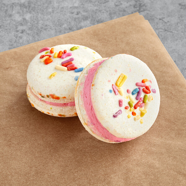 Two Macaron Centrale vegan birthday macarons with colorful sprinkles on top.