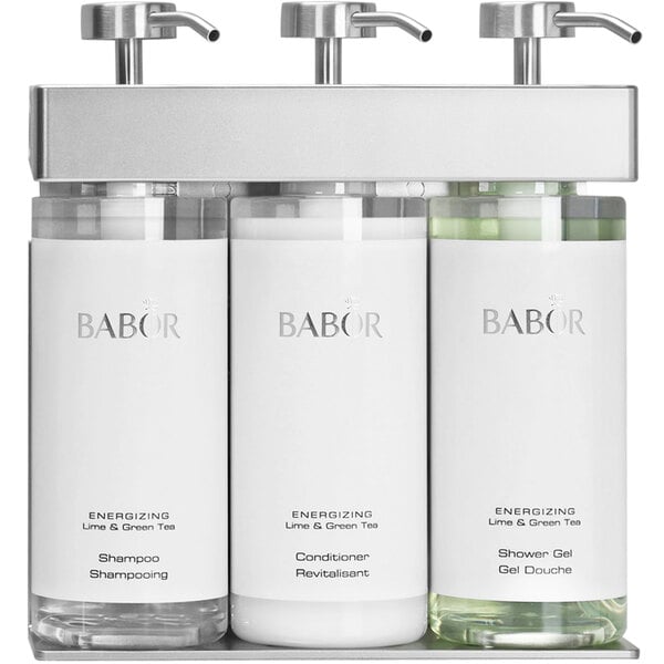 A white rectangular Dispenser Amenities wall mounted shower dispenser with silver text and 3 oval bottles with green Babor labels.