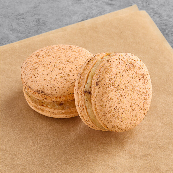 Two Macaron Centrale Masala Chai macarons on brown paper.