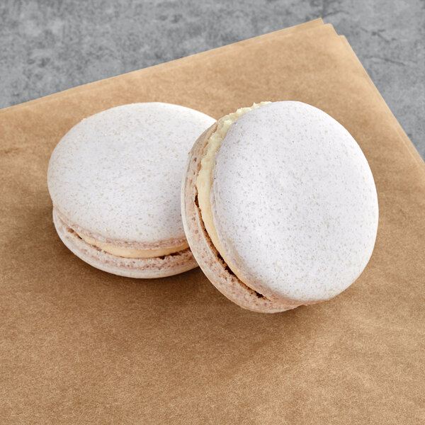 Two Macaron Centrale balsamic fig macarons on a brown surface.