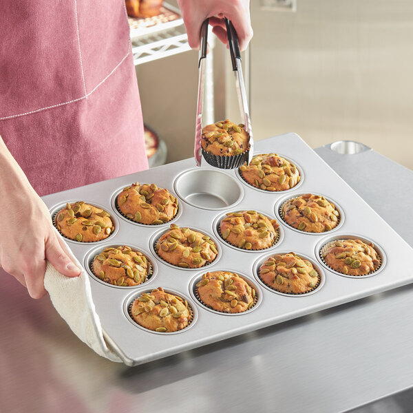 A woman holding a Baker's Mark jumbo muffin pan with muffins in it.