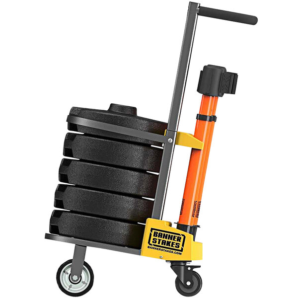 A hand truck with a stack of black and orange Banner Stakes drums.